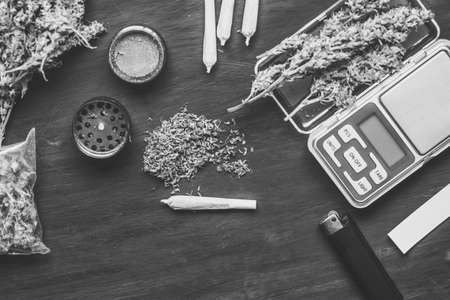 Marijuana, scales, jambs and a cannabis grinder on a black wooden table topの写真素材