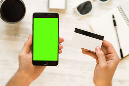 Hand holding black smartphone with green screen chroma key compositing Online payments plastic card Smartphone with green screen for chroma key compositingの写真素材