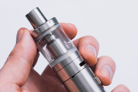Man hand shows vape device at cloud of vapor background. Vape concept, toned Vapeの写真素材