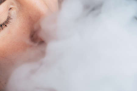 Smoke on a black background. A woman smokes cannabis weed, a joint and a lighter in his hands. Concepts of medical marijuana use and legalization of the cannabis. On a black backgroundの写真素材