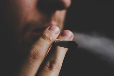 smokes weed cannabis, A man joint in his hands. Smoke on a black background. Concepts of medical...