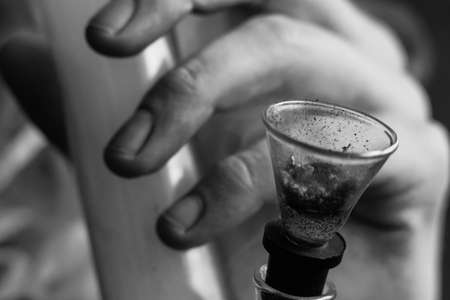 Bong smokes cannabis weed, a joint and a lighter in his hands. Smoke on a black background. Concepts of medical marijuana use and legalization of the cannabis. On a black backgroundの写真素材