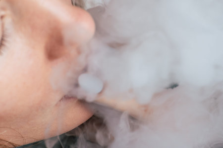 A woman smokes weed cannabis a joint and a lighter in his hands. Smoke on a black background. Concepts of medical marijuana use and legalization of the cannabis. On a black backgroundの写真素材