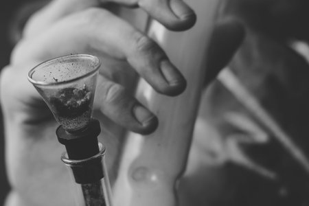 Bong smokes cannabis weed, a joint and a lighter in his hands. Smoke on a black background. Concepts of medical marijuana use and legalization of the cannabis. On a black backgroundの写真素材