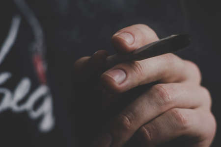 A man smokes cannabis weed, a joint and a lighter in his hands. Smoke on a black background. Concepts of medical marijuana use and legalization of the cannabis. On a black backgroundの写真素材