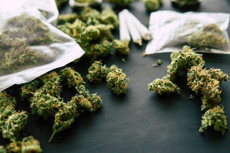 Macro of marijuana with trichomes and crushed weed in a grinder for chopping a canapis on a black table clouse upの写真素材