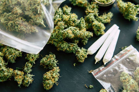 rolled jamb joint in the hands of a man marijuana weed and grinder for weed, concepts of smoking marijuana, dark background close up, top viewの写真素材