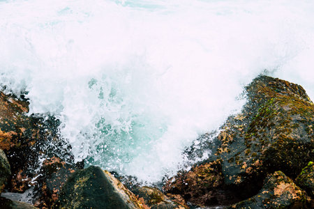 Danger sea wave crashing on rock coast with spray and foam before storm in Positano, Italy