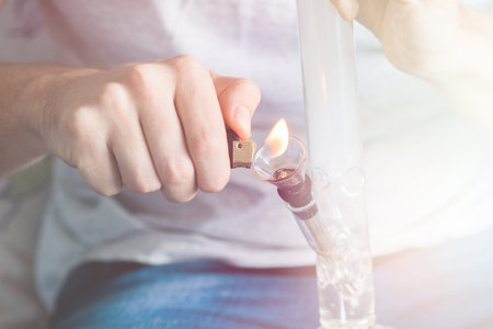 man using a smartphone. Bong and medical marijuana, cannabis thc flower Sativa and Indica Close up...
