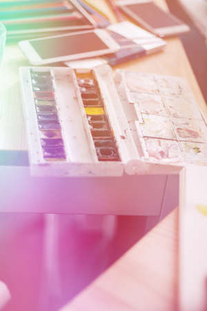 Mock up. Creative space. Artistic work tools on dark wooden table: watercolor, paintbrushes and water.の写真素材