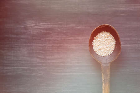A spoon of seed seeds in a natural wooden spoon in rustic style against the background of a natural textured tree of dark color. With a wire for signingの写真素材