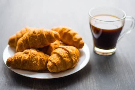 American coffee and fresh croissants on a black background.