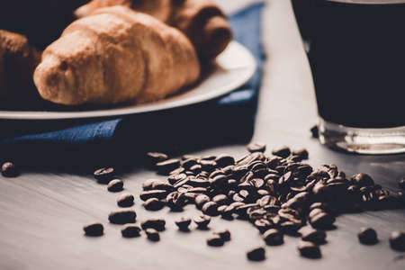 Dessert and coffee beans. Top view. Macro shot of fresh croissants and coffee on a black background. Mate moody color. concept of breakfast.の写真素材
