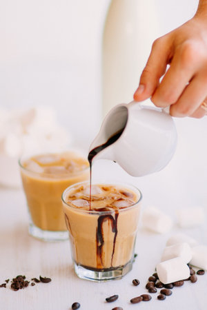 Concept of a cooling drink. Marshmelow and coffee beans on the table. Summer drink. Cold coffee with...