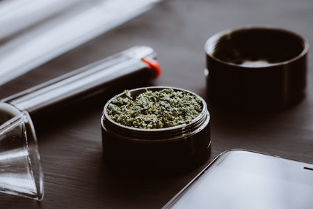 Dark background. Close up Cannabis buds in grinder on the table Marijuana with a grinder. Toning...