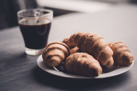 The concept of breakfast. Macro shot. American coffee and fresh croissants on a black background. Mate moody color. Dessert and coffee.の写真素材