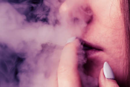 Smoke on a black background. A woman smokes cannabis weed, a joint and a lighter in his hands. Concepts of medical marijuana use and legalization of the cannabis.の写真素材