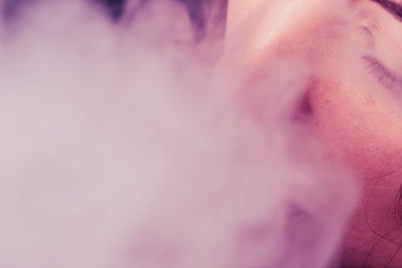 A woman smokes cannabis weed, a joint and a lighter in his hands. Smoke on a black background. Concepts of medical marijuana use and legalization of the cannabis.の写真素材