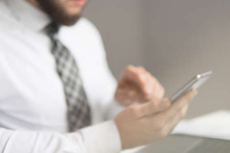 Businessman work with computer on table in office work. Financial business. Light background. Office work with a laptop. Smartphone in hand. Close up. Young bearded businessman.の写真素材