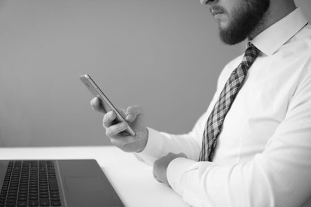 Office work with a laptop. Young bearded businessman. Light background. Financial business. Holding...