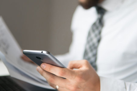 Financial business. Light background. Office work with a laptop. Businessman work with computer on table in office work. Young bearded businessman. Holding smartphone in hand.の写真素材