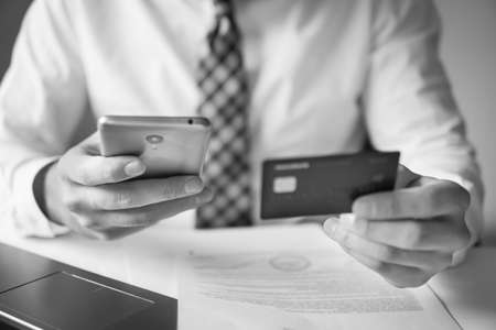 Smartphone and Internet Commerce. Young businessman with a bank credit card in his hands. Payment of goods online. Online payments through the phone. Online trading on the currency exchange.の写真素材