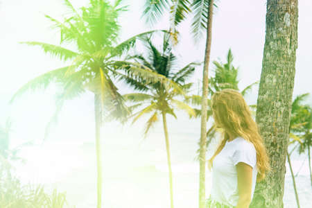 Beautiful young sexy woman model with perfect figure, bright makeup, wearing orange dress with python pattern, in palm leaves in the jungle, shadows, shining sun, free place for text. Fashion photoの写真素材