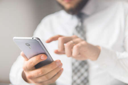 Businessman uses a smartphone. Office work concept. Shopping online. sending email, mobile phone. Close up telephone. White background.の写真素材