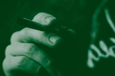 A man smokes cannabis weed, a joint and a lighter in his hands. Smoke on a black background. Concepts of medical marijuana use and legalization of the cannabis. On a black backgroundの写真素材