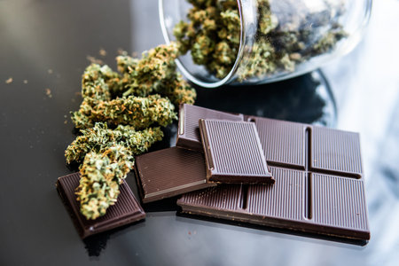 Chocolate with cannabis and buds of marijuana on the table. Concept of chocolate with cannabis herb...