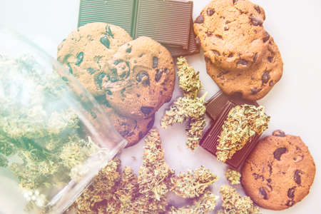 Treatment of medical marijuana for use in food, white background. Cookies with cannabis and buds of marijuana on the table. Cookies with cannabis herb CBD. light leaksの写真素材