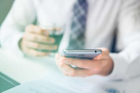 Close up telephone. Businessman working with documents White background. Shopping online. Office work concept. Businessman uses a smartphone. Sending email, mobile phone.の写真素材