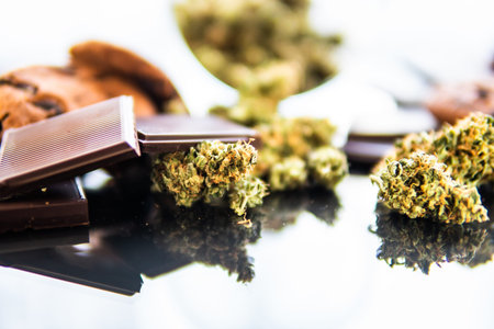 Chocolate and Cookies with cannabis and buds of marijuana on the table. Concept of Cookies and...