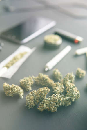 marijuana buds on black table, joint with weed, grinder in hand with fresh Cannabis, close up, light leaks color tones vertical shotの写真素材