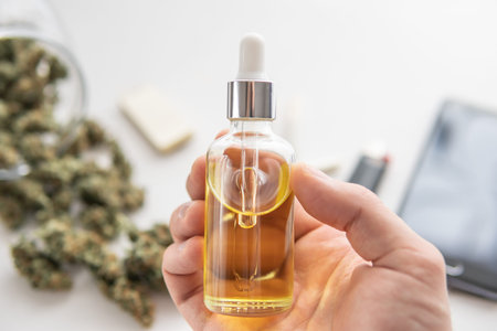 CBD cannabis OIL, bottle of Cannabis oil in pipette in hand, close up, hemp product, medical...