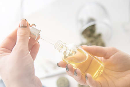 medical hemp concept, close up, marijuana extract on white background, oil Cannabis CBD in pipette women hand, weed product, light leaks color tonesの写真素材