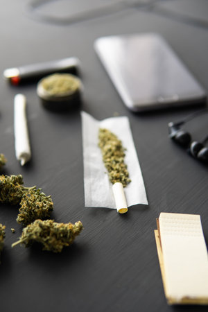 marijuana buds on black table, close up, joint with weed, grinder in hand with fresh Cannabis,...