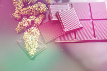 Concept of chocolate with cannabis herb CBD. Treatment of medical marijuana for use in food, black background. Chocolate with cannabis and buds of marijuana on the table.の写真素材