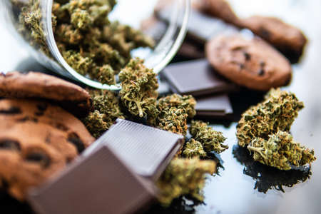 Chocolate and Cookies with cannabis and buds of marijuana on the table. Concept of Cookies and chocolate with cannabis herb CBD. Treatment of medical marijuana for use in food, black background.の写真素材