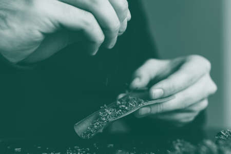 Man rolling a marijuana weed blunt. Close up marijuana joint with lighter. Man rolling marijuana cannabis blunt. green tonedの写真素材