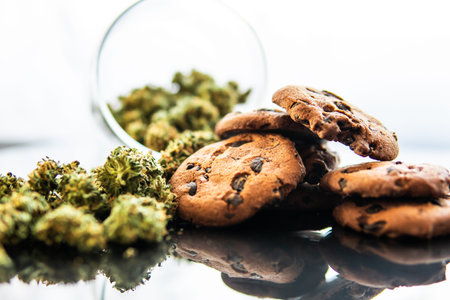 Concept of cooking with cannabis herb CBD. Cookies with cannabis and buds of marijuana on the table. Treatment of medical marijuana for use in food, black background.の写真素材