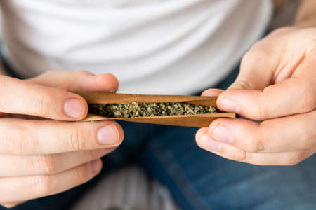 marijuana GRINDER cannabis use concept. Close up of Man rolling a cannabis blunt on white background. Man preparing and rolling marijuana cannabis blunt.の写真素材