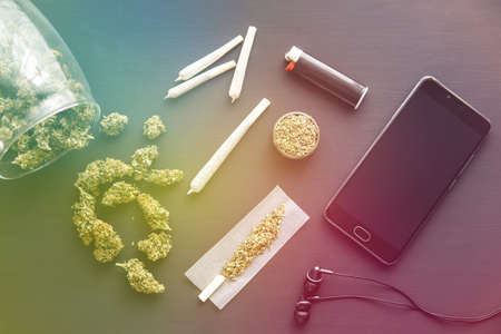joint with weed, grinder in hand with fresh Cannabis, marijuana buds on black table, close up, light leaks color tonesの写真素材
