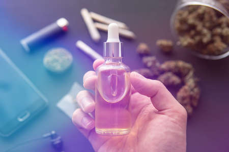 medical marijuana concept, Hand holding bottle of Cannabis oil in pipette, natural herb, CBD cannabis OIL. close up, hemp product, light leaks color tonesの写真素材