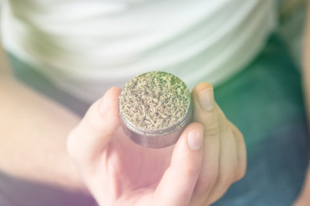 marijuana GRINDER cannabis use concept. Man preparing and rolling marijuana cannabis joint. Close up of Man rolling a cannabis joint on white background.の写真素材