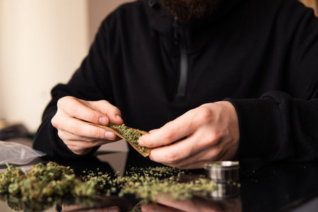 Close up marijuana joint with lighter. Man rolling marijuana cannabis blunt. Man rolling a marijuana weed blunt.の写真素材