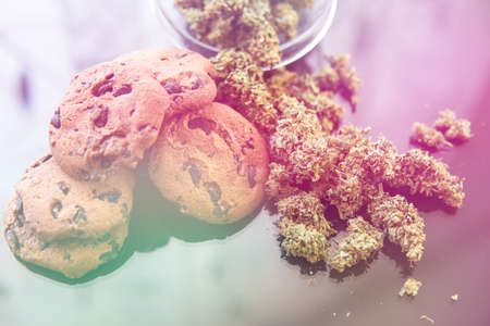 Concept of cooking with cannabis herb. Treatment of medical marijuana for use in food, black background. Cookies with cannabis and buds of marijuana on the table. light leaksの写真素材