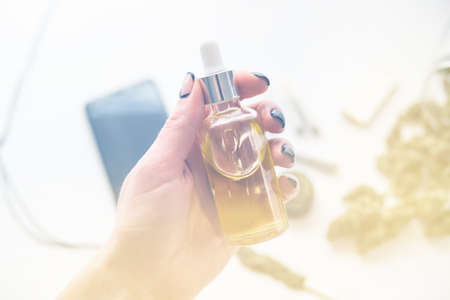 oil Cannabis CBD in pipette women hand, marijuana extract on white background, weed product, close up, medical hemp concept, light leaks color tonesの写真素材