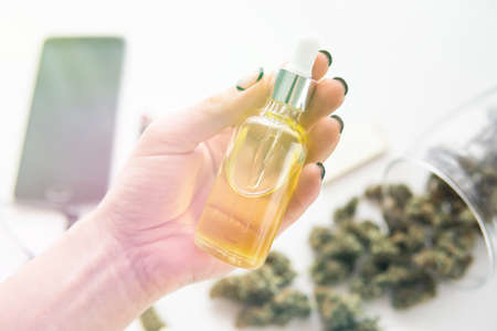 weed product, marijuana extract on white background, medical hemp concept, close up, oil Cannabis CBD in pipette women hand, light leaks color tonesの写真素材