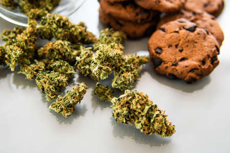 Treatment of medical marijuana for use in food, white background. Cookies with cannabis and buds of marijuana on the table. Cookies with cannabis herb CBD.の写真素材
